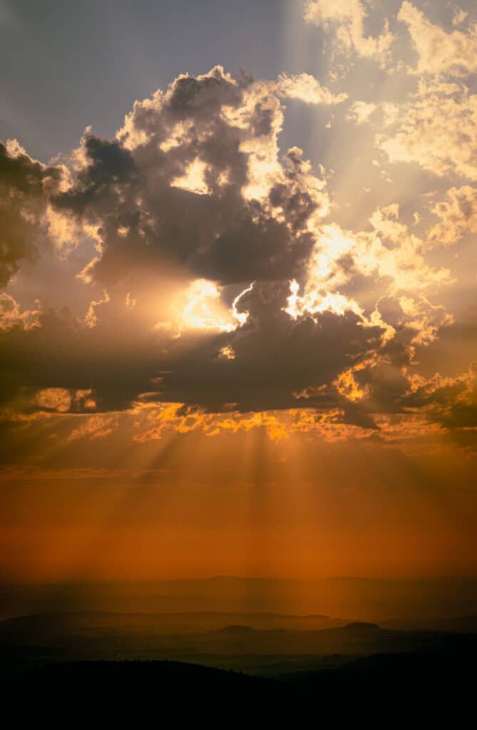 Beautiful orange and yellow sun covered by clouds in mountains