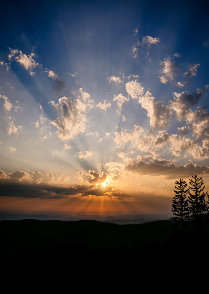 Beautiful orange and yellow sun covered by clouds in mountains