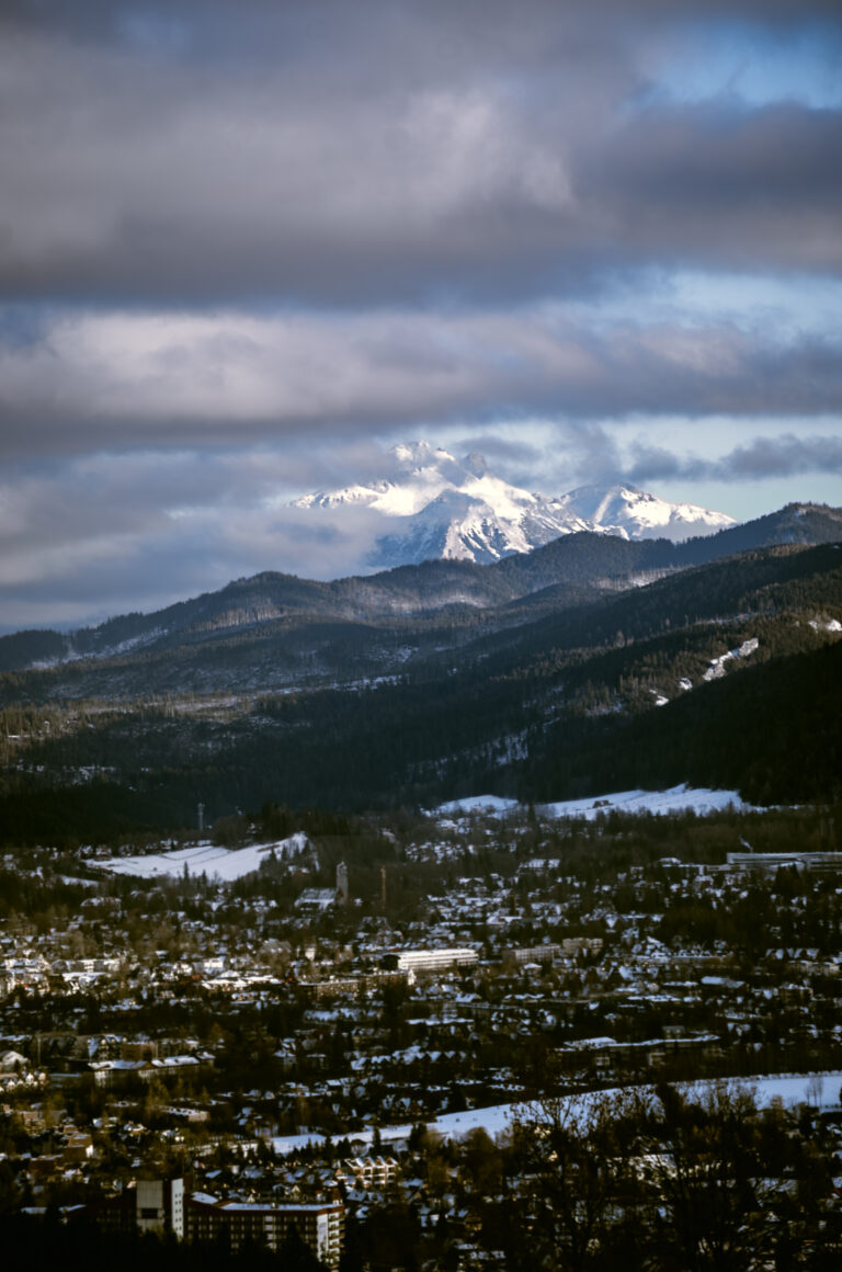 snow-capped mountains shrouded in clouds at sunset and a snow-covered town in the valley