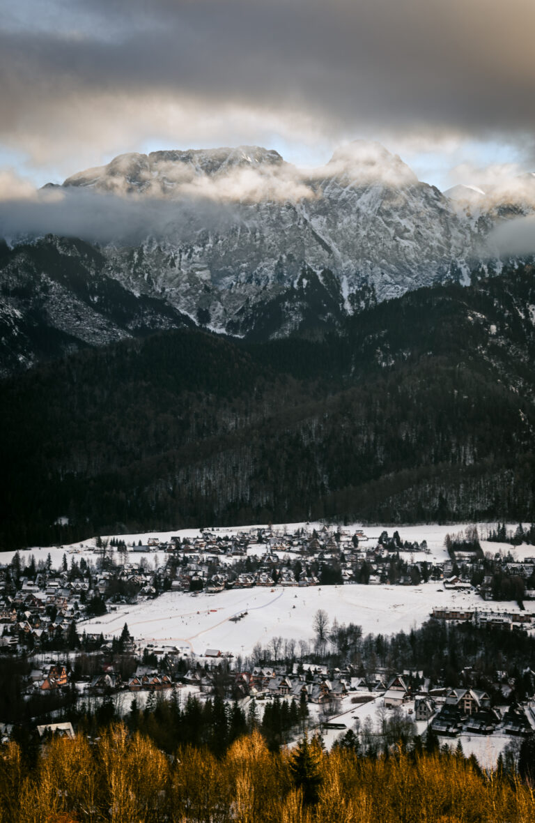 snow-capped mountains shrouded in clouds at sunset and a snow-covered town in the valley