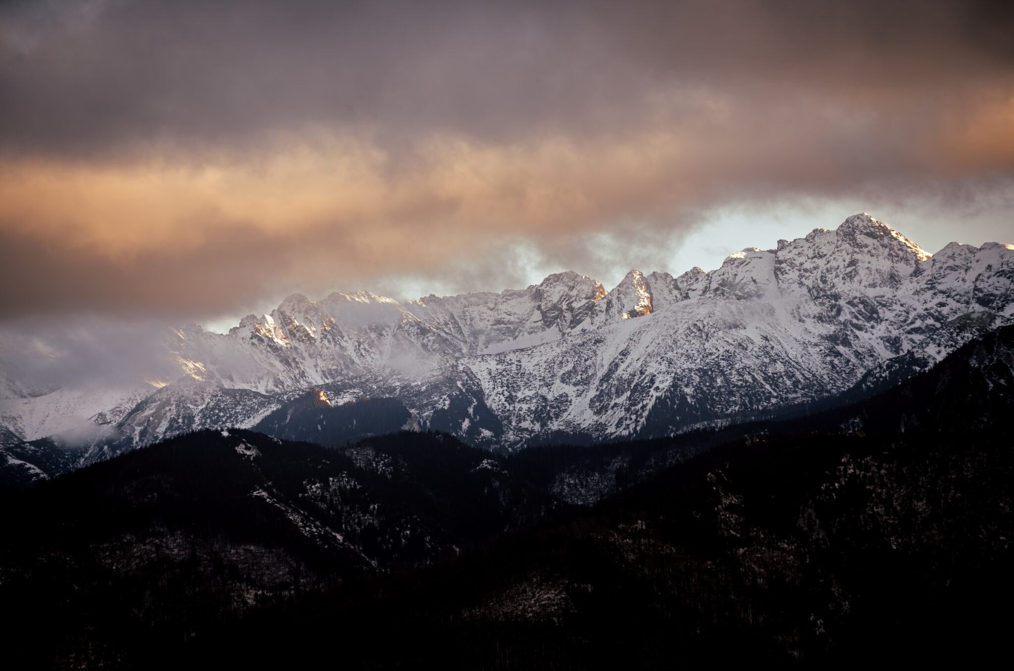 snow-capped mountains shrouded in clouds at sunset