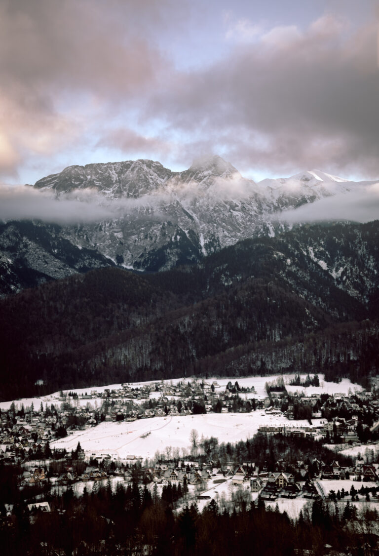 snow-capped mountains shrouded in clouds at sunset and a snow-covered town in the valley