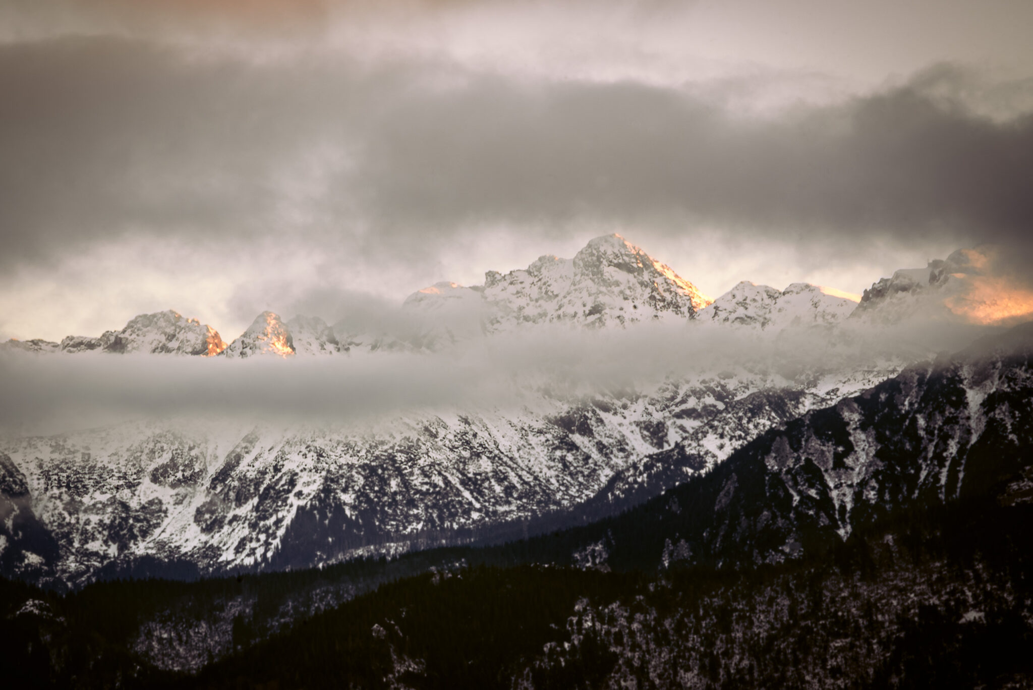 snow-capped mountains shrouded in clouds at sunset